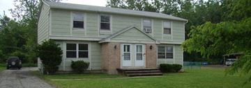 Amherst triplex for rent - a white house with a white door and a green and brick porch