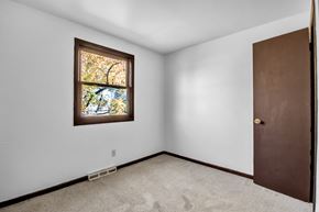 Amherst triplex for rent - A room with a brown door and a window with a view of trees.
