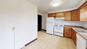 Amherst triplex for rent - A kitchen with white appliances and wooden cabinets.