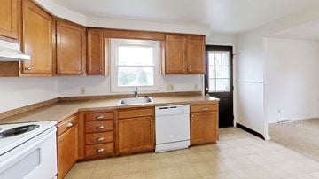 Amherst triplex for rent - A kitchen with wooden cabinets and a white dishwasher.