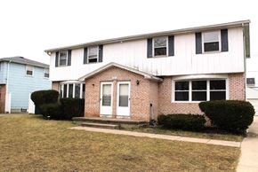 Amherst triplex for rent - a white and brick house with a porch and a sidewalk