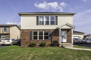 Amherst triplex for rent - the front of a house with cars parked in a parking lot