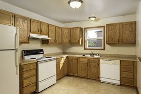 Amherst triplex for rent - a kitchen with white appliances and wooden cabinets