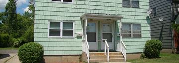 Buffalo triplex for rent - A green house with a white door and windows.