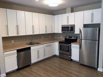 Duxbury apartment for rent - an empty kitchen with white cabinets and stainless steel appliances