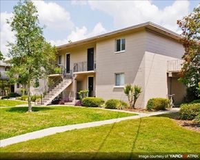 Gainesville apartment for rent - a white apartment building with a yard and stairs