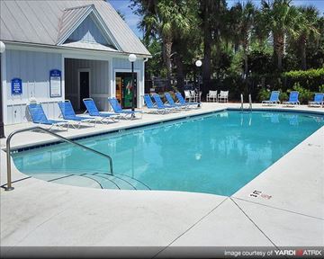 Gainesville apartment for rent - a swimming pool with blue chairs and a white building