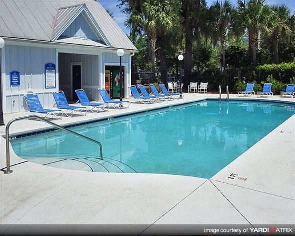Gainesville apartment for rent - a swimming pool with blue chairs and a white building