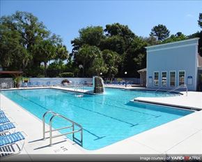 Gainesville apartment for rent - a large swimming pool with a building and chairs