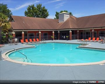 Gainesville apartment for rent - a swimming pool with orange chairs in front of a building