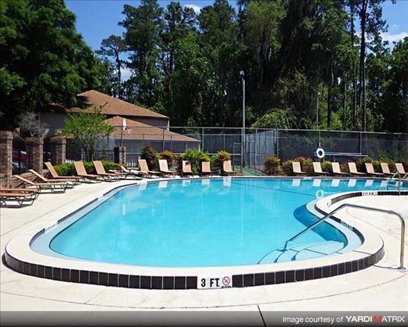 Gainesville apartment for rent - a large swimming pool with chairs around it