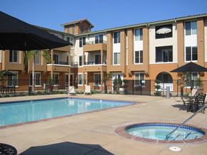 San Jose apartment for rent - A large swimming pool in front of a building with a black umbrella.