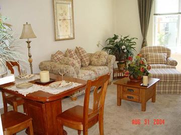 San Jose apartment for rent - A living room with a couch, chair, and table set for a meal.