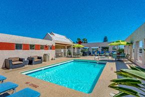 Los Angeles apartment for rent - a resort style pool with chairs and umbrellas in front of a house