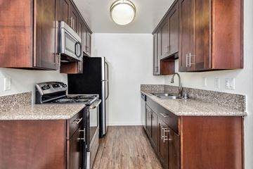 West Hollywood apartment for rent - a kitchen with wood cabinets and granite counter tops and a black refrigerator