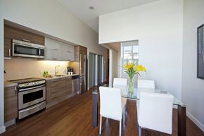 Toronto apartment for rent - A modern kitchen with a glass dining table and white chairs.
