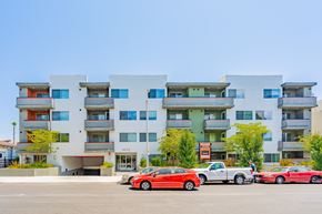 Los Angeles apartment for rent - A red car is parked in front of a white building with balconies.