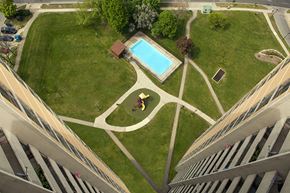 North York apartment for rent - A man is walking in a park with a swimming pool.
