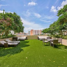 West Palm Beach apartment for rent - A sunny day at the rooftop garden with green grass and furniture.