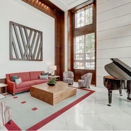 West Palm Beach apartment for rent - A living room with a red couch, a wooden coffee table, and a grand piano.