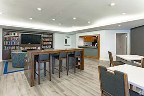West Palm Beach apartment for rent - A modern room with a long table and chairs, a television, and a bookshelf filled with books.