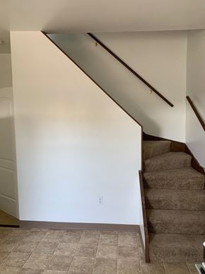 Glassport house for rent - A staircase with a brown carpeted runner and wooden handrails.