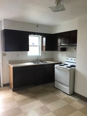 Glassport house for rent - A kitchen with black cabinets and a white stove top oven.
