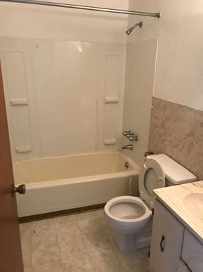 Glassport house for rent - A white toilet in a bathroom with a white tub and a white sink.