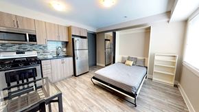 Ottawa apartment for rent - a bedroom with a bed and a kitchen with stainless steel appliances