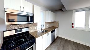 Ottawa apartment for rent - a kitchen with white cabinets and a stove and a microwave
