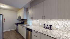 Ottawa apartment for rent - a kitchen with white cabinets and a counter with a eat sign