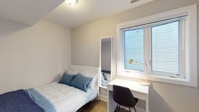Ottawa apartment for rent - a bedroom with a bed and a desk and a window