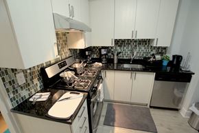Ottawa apartment for rent - a kitchen with white cabinets and black counter tops and a stove
