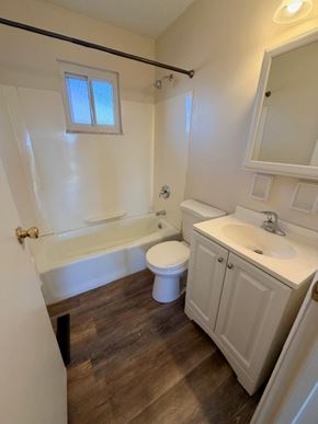 Hilliard apartment for rent - A small white bathroom with wood flooring and a window.