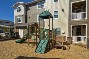 Charlotte apartment for rent - Community playground featuring colorful play equipment, including slides and climbing features, located within a courtyard setting.