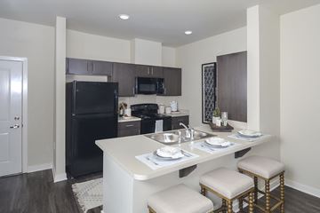 Charlotte apartment for rent - A kitchen with a black refrigerator, a white counter, and a white dining table with four chairs.