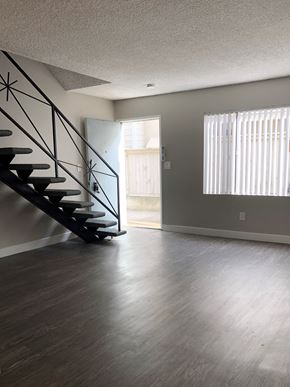 Redondo Beach apartment for rent - A room with a wooden floor and a staircase with a black railing.