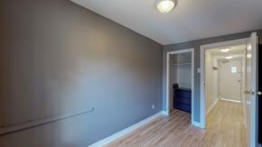 Ottawa apartment for rent - a bedroom with grey walls and a door to a closet and a hallway with wood