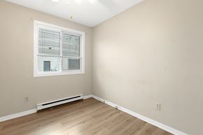 Ottawa condo for rent - a bedroom with white walls and a window and wooden floors