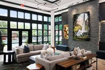 Nashville apartment for rent - A modern living room with a large window and a painting of a waterfall on the wall.
