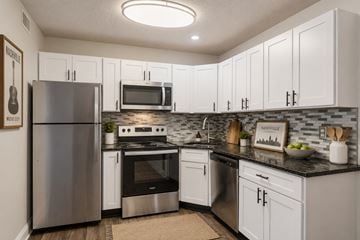 Nashville apartment for rent - A kitchen with white cabinets and a black countertop.