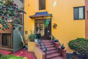 Oakland apartment for rent - A yellow house with a red staircase leading to the front door.