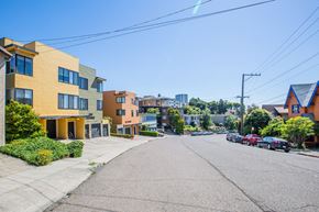 Oakland apartment for rent - A street view of a residential area with houses and parked cars.