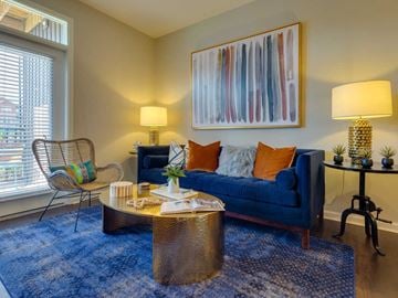 Fort Mill apartment for rent - A living room with a blue couch, a chair, a coffee table, and a painting on the wall.