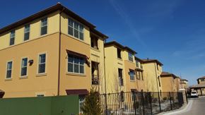 Reno apartment for rent - a row of yellow houses with a fence and a blue sky