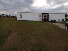Beech Island house for rent - A white building with a darker roof is surrounded by a grassy field.