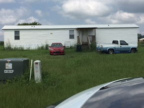 Beech Island house for rent - A white trailer is parked in a grassy field with a red car and a blue truck behind it.