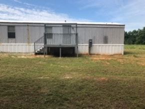 Honea Path house for rent - A large metal building with a balcony and a door is situated in a grassy field.