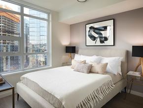 Seattle apartment for rent - A bedroom with a large bed and a large window overlooking a construction site.