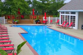 North Royalton apartment for rent - a large swimming pool with red chairs and a pool house